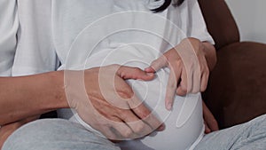 Young Asian Pregnant couple making heart sign holding belly. Mom and Dad feeling happy smiling peaceful while take care baby,