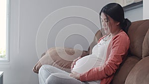 Young Asian Pregnant woman holding her belly talking with her child. Mom feeling happy smiling positive and peaceful take care