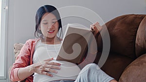 Young Asian Pregnant woman read a book for baby in belly. Mom feeling happy smiling positive and peaceful while take care child