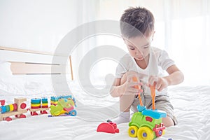 Young boy playing toys on bed