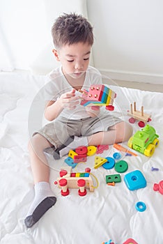 Young boy playing toys on bed