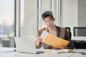 Young Asian professional business man receiving business mail letter in office.