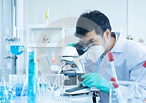 Young Asian researcher using modern microscope in laboratory