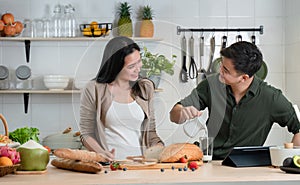 Young Asian romantic couple is cooking in the kitchen. A beautiful woman and handsome man making healthy breakfast food
