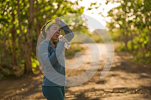 Young Asian runner girl drinking water sweaty and tired. Attractive and exhausted Korean woman thirsty after running workout and