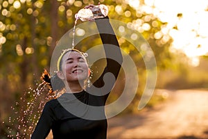 Young Asian runner girl refreshing drinking and pouring water on her head. Attractive and happy Chinese woman tired after running