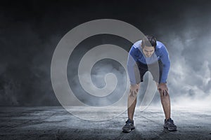 Young asian runner man taking rest from jogging