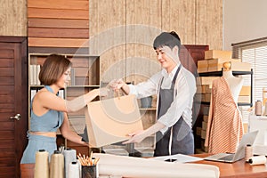 Young asian sales man gives shopping bag with purchased merchandise and clothes to woman customer, Beautiful female buying dress