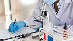 Young Asian scientist Working looking through a microscope doing research for analyzing a Experiments sample in a forensic