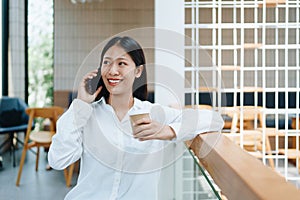 A young Asian self employed woman showing a smiling face and happiness while using smartphone mobile talking business