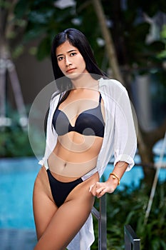 Young asian sexy girl in a white bikini posing at hotel territory