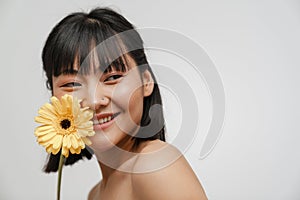 Young asian shirtless woman smiling while posing with gerbera flower