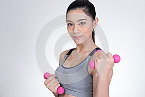 Young asian sporting woman training with dumbbell. Pretty athletic girl making physical exercise against white background. Health