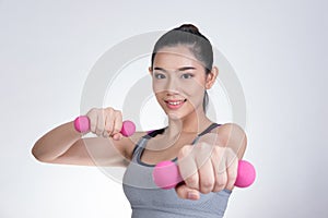 Young asian sporting woman training with dumbbell. Pretty athletic girl making physical exercise against white background. Health