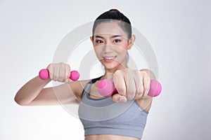 Young asian sporting woman training with dumbbell. Pretty athletic girl making physical exercise against white background. Health