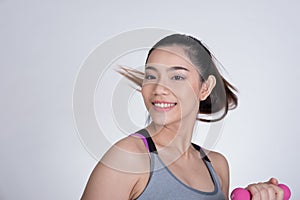 Young asian sporting woman training with dumbbell. Pretty athletic girl making physical exercise against white background. Health