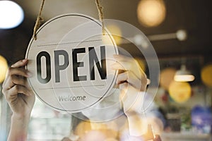 Young asian staff woman wearing protection face mask turning open sign board on glass door