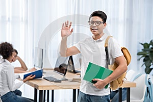 young asian student boy waving hand in classroom