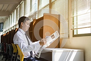 Young Asian student reading newspaper