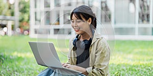 Young Asian student sitting and using laptop at university before class room. education, back to school concept