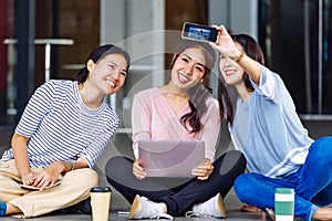Young Asian students taking a selfie photo and laughing at university campus