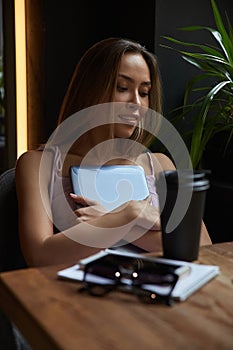 young asian stylish pretty woman sitting at table of coffee shop, holding laptop