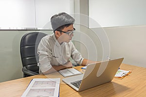 Young Asian supervisor working on laptop and statistic documents