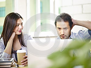 Young asian teammates working together in office using laptop co