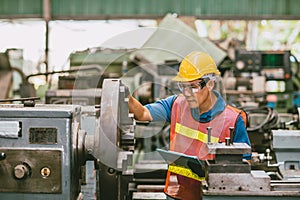 Young Asian Technician Engineer Staff Worker using Lathe CNC Milling Machine work in Heavy Metal Factory