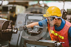 Young Asian Technician Engineer Staff Worker using Lathe CNC Milling Machine work in Heavy Metal Factory.