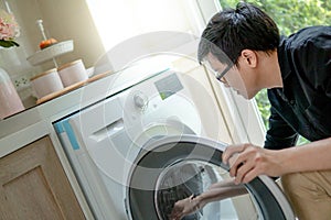 Asian technician looking into washing machine