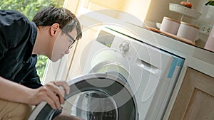 Asian technician looking into washing machine