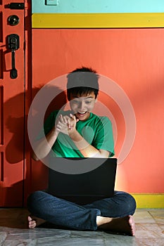 Young asian teen with a laptop computer in a living room