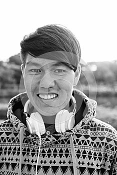 Young Asian teenage boy wearing headphones while relaxing at the park