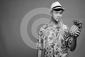 Young Asian tourist man ready for vacation against gray background