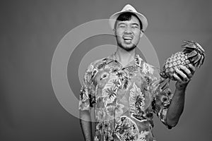 Young Asian tourist man ready for vacation against gray background