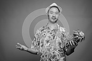 Young Asian tourist man ready for vacation against gray background