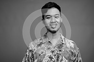 Young Asian tourist man ready for vacation against gray background