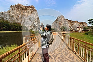 Young Asian tourist taking a picture of rocky mountain of khao Ngu Stone Park , Ratchaburi , Thailand.