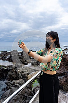 Young Asian tourist woman taking a photo with her smartphone.