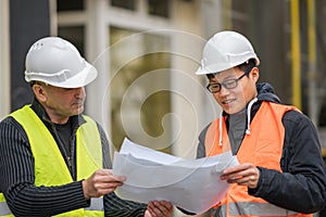 Asian apprentice engineer at work on construction site with the senior manager