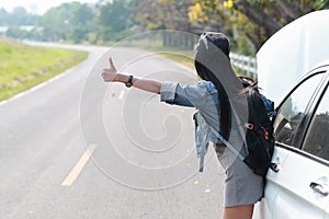 Young asian traveler with backpack and map hitchhiking on the road while traveling during holiday vacation