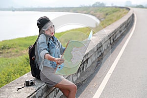 Young asian traveler with backpack searching direction on location map and using smart phone while traveling during holiday vacati