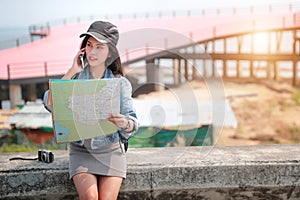 Young asian traveler with backpack searching direction on location map and using smart phone while traveling during holiday vacati