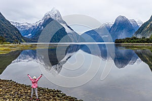 Young Asian traveler celebrating success at Milford Sound, Fiordland National Park, South Island, New Zealand
