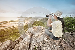 Young Asian traveler woman looking a binoculars.