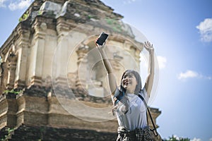 Young Asian traveler woman smiling while traveling around Thai ancient temple on holidays vacation