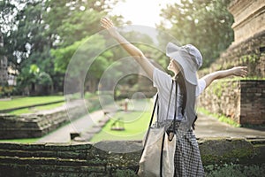 Young Asian traveler woman smiling while traveling around Thai ancient temple on holidays vacation