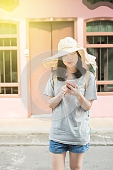 Young Asian traveling blogger or backpacker using route application on the mobile phone to find the needed address in a city
