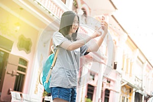 Young Asian traveling blogger or backpacker using route application on the mobile phone to find the needed address in a city.